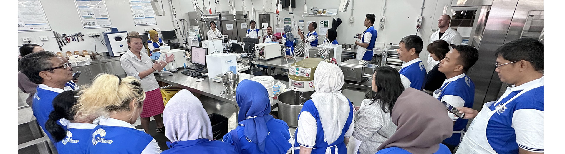 Group of people listen to someone talking in a bakery