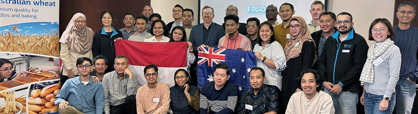 Group of people posing for the camera. Two of them hold an Australian and Indonesian flag